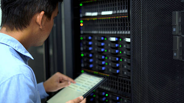m5 An IT technician inspects and manages a server rack in a data center using a tablet, representing cloud computing, cybersecurity, and network infrastructure maintenance.